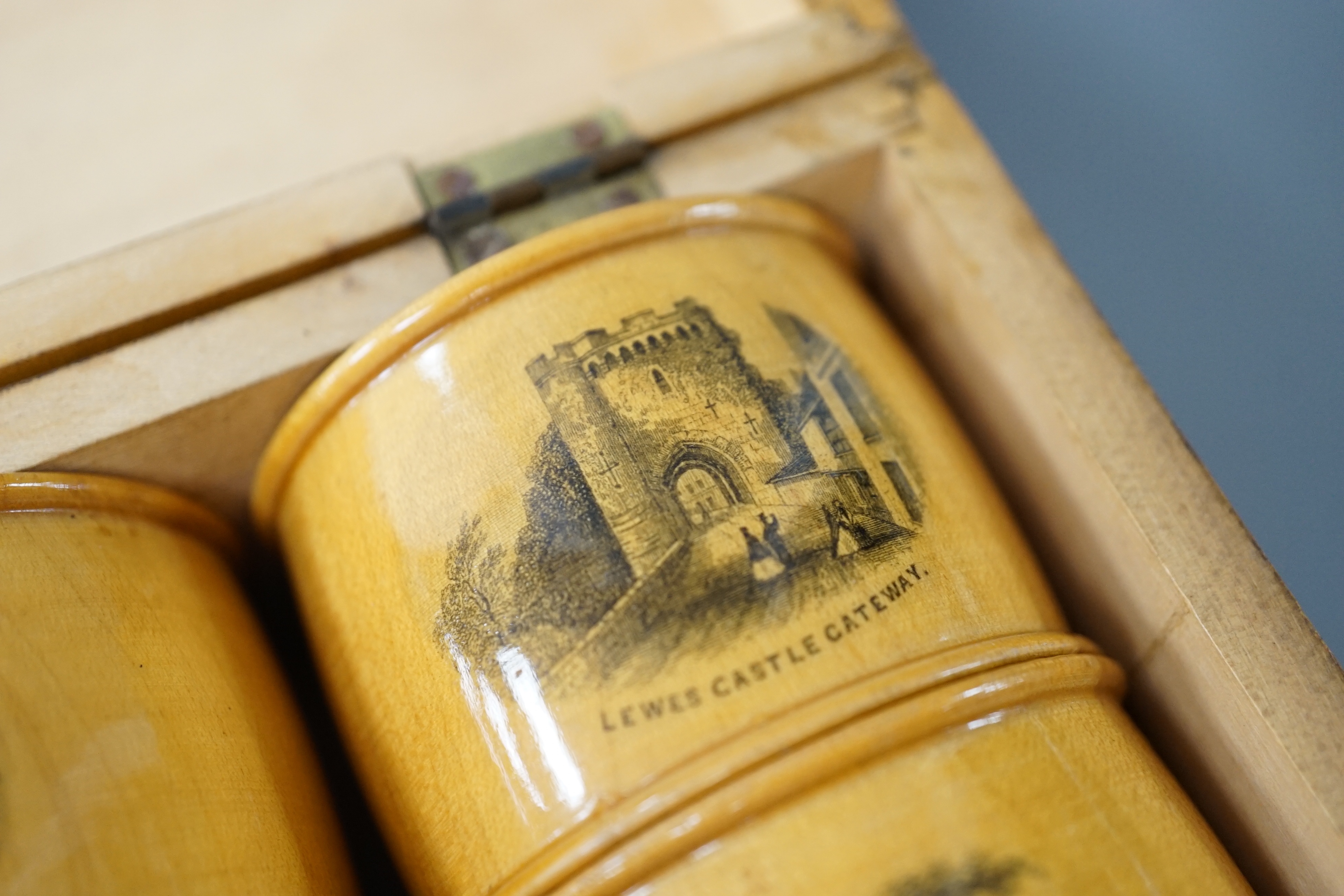 A set of 6 late 19th century mauchline ware napkin rings decorated with scenes of Lewes, housed in matching box. 18cm